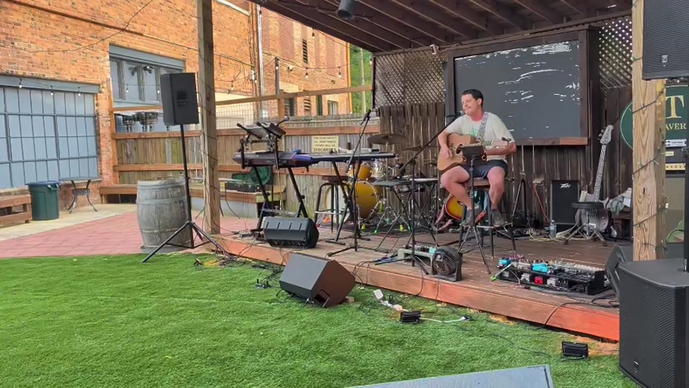 Matthew Freeman performing acoustic guitar on the outdoor stage at KT's Tavern